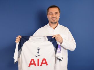 Bild zeigt, wie Dr. Abdulaziz Balwi ein Trikot des Premiere League Klubs Tottenham Hotspur in beiden Händen hält
