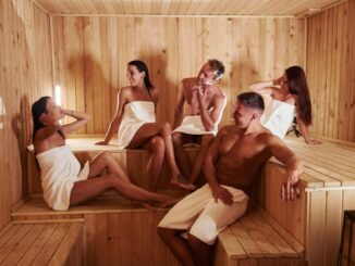 mehrere Personen sitzen in einer Sauna aus Holz